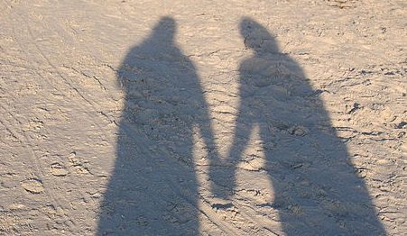 510px-Holding_Hands_shadow_on_sand